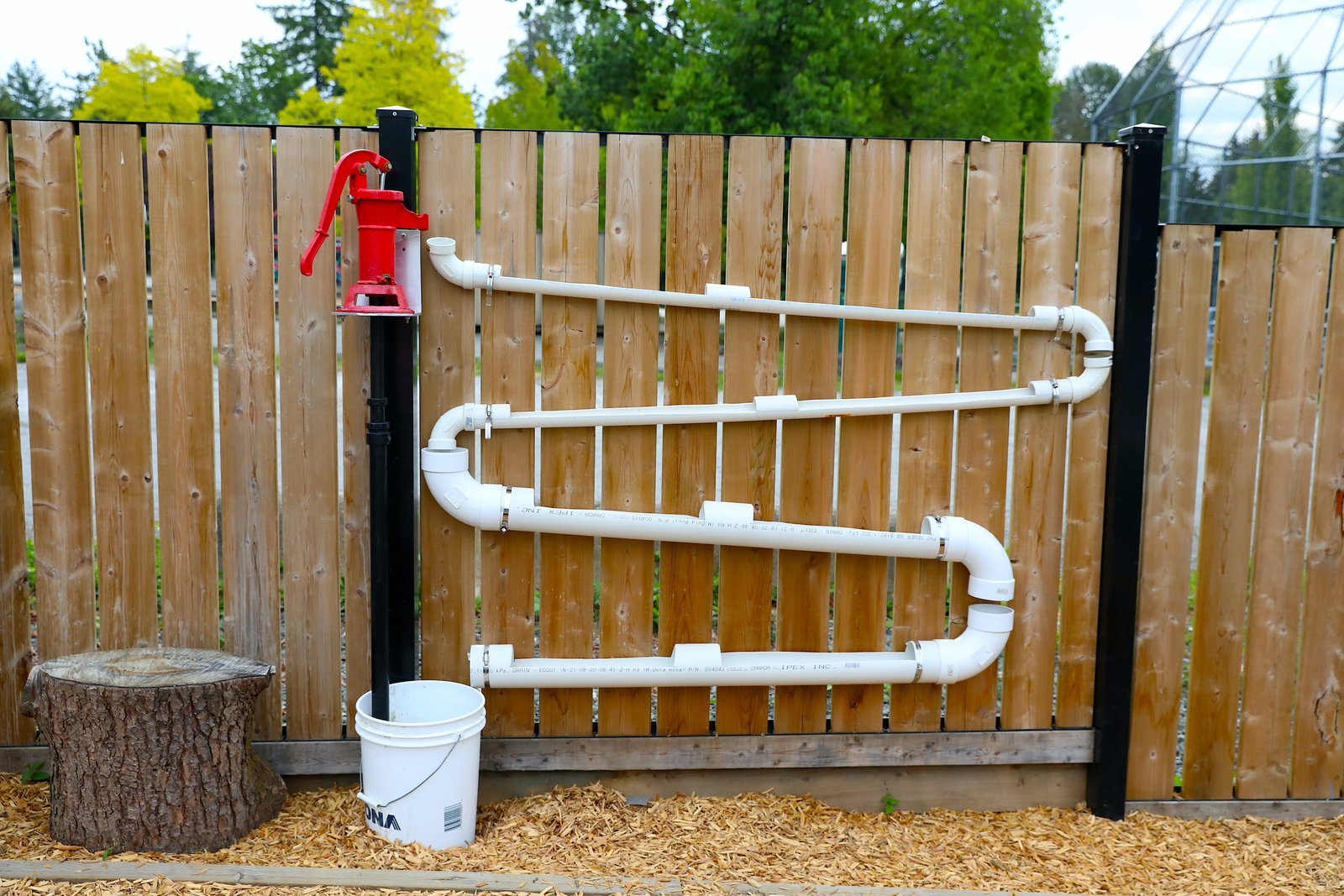 Hand pump and looping PVC pipe water wall on the fence